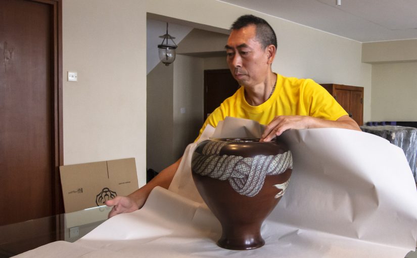 An Asian Tigers crew member hand-wrapping a ceramic vase to FIDI standard